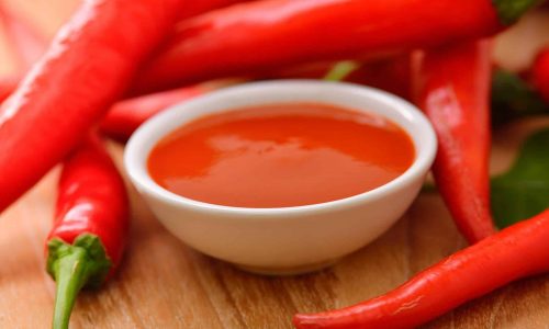 chilli sauce with red hot chili on wooden background